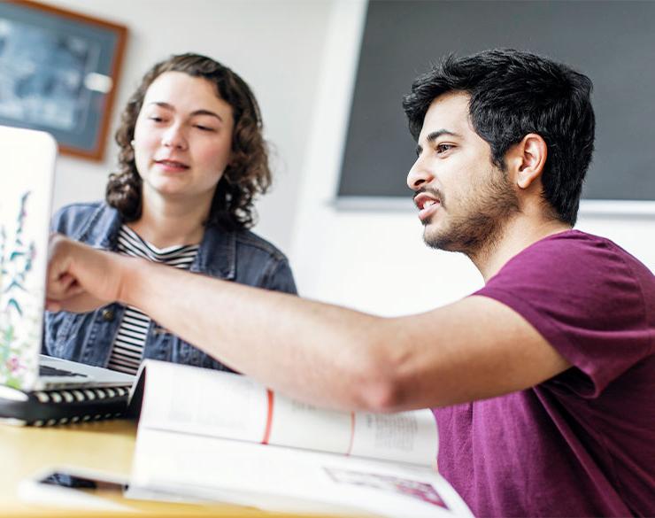 一个学生指着另一个学生的笔记本电脑. 